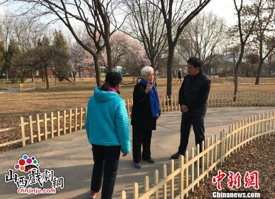 图为阎惠贞在公园与戏迷交流切磋。 杨静 摄 图为阎惠贞在公园与戏迷交流切磋。 杨静 摄